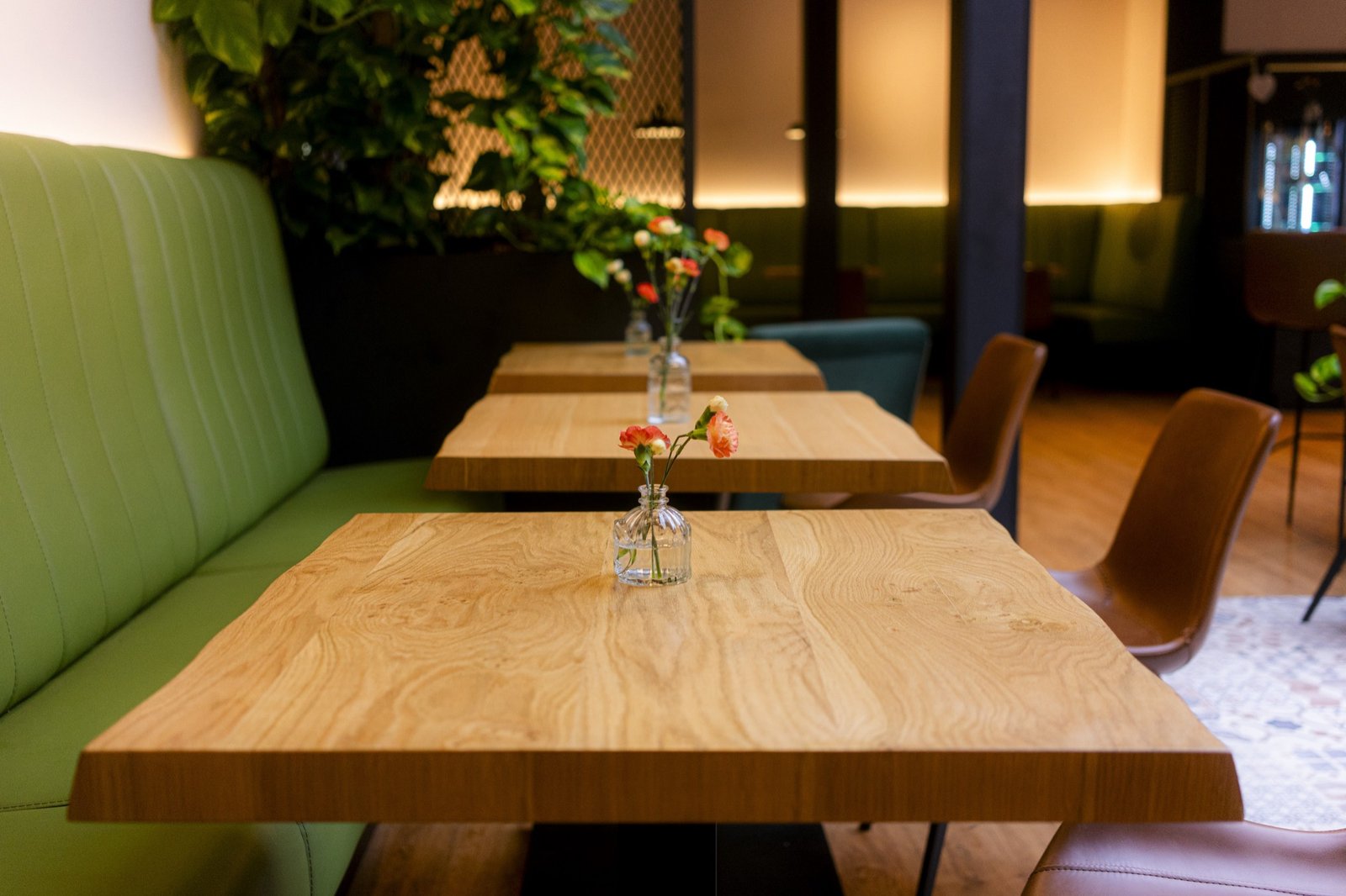 Eichentische mit kleinen Blumenvasen und grüner Sitzbank im Wohnzimmer